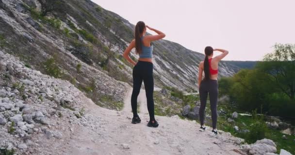 Две спортивные дамы в середине удивительного ландшафта на природе остановились на перерыв глядя вдаль, чтобы увидеть всю красоту природы вокруг — стоковое видео