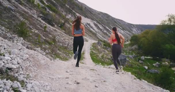 Correre sul tetto in cima alla natura due signore con un corpo perfetto in forma, in una giornata estiva accanto a grandi montagne — Video Stock