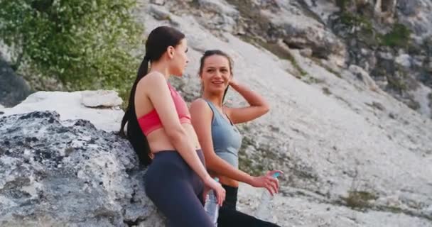 Attraktiva sportiga damer samtidigt har sin träning rutin stannade för ett ögonblick att dricka lite vatten och ta lite frisk luft i naturen — Stockvideo