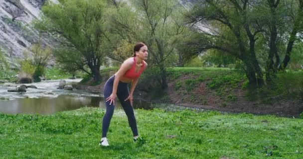 Спортивная леди с большим подходящим телом растягивая ноги и все тело в середине удивительный вид на ландшафт, имеют тренировки полного тела упражнения — стоковое видео