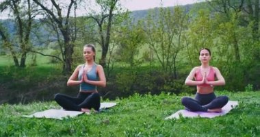 Doğada çekici kadınlar yoga yaparken konsantre nehir ve yeşil alan ile inanılmaz dağ yerinde bazı temiz hava alırken meditasyon pozlar