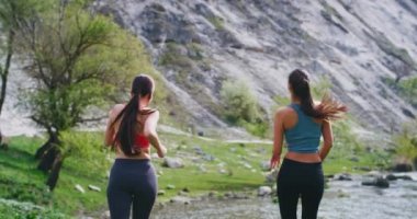 Kablosuz airpods ile müzik dinlerken doğanın ortasında çalışan Mutlu fit bayanlar onlar sert bir egzersiz sonrası etrafında manzara zevk nehrin çatısında biraz durdu