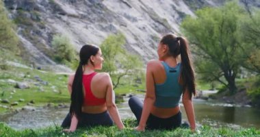 Doğada inanılmaz güzel bir yerde iki sportif bayanlar bir egzersiz gününden sonra onlar sohbet ve heyecanlı duygu büyük bir nehrin yanında çim üzerinde otururken zaman zevk