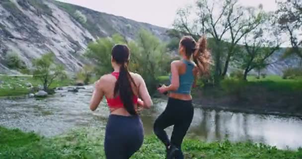 Привлекательные дамы с подходящими телами после бега тренировки устали остановились на немного в удивительном пейзаже, чтобы подышать свежим воздухом и расслабиться — стоковое видео