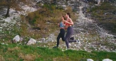 Güneşli bir günde dağ yolunda sıkı koşan çok güzel genç bayanlar, fit vücutları ve kas bacakları ile sert bir egzersiz pratik