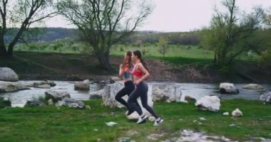 Nehir ve yeşil alan etrafında şaşırtıcı manzara ile dağ yolunun ortasında sert çalışan uygun organları ile iyi görünümlü iki kadın, onlar büyük bir ruh hali ve enerji çok var