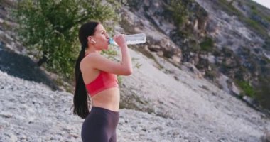 Dağ sportif bayan ortasında çok zor bir egzersiz biraz su içme ve kablosuz airpods müzik dinlerken hala montaj yol üzerinden çalışan sonra susuz