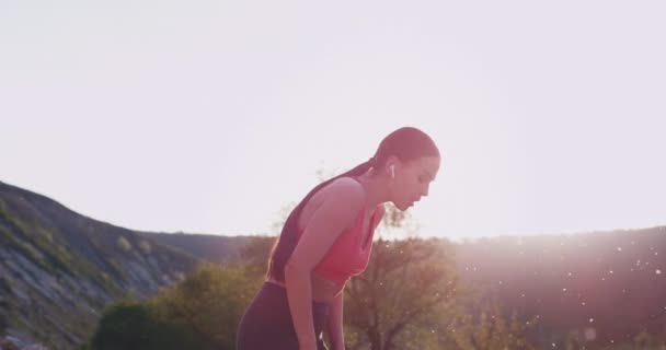 Cansada mujer guapa después de un duro día de entrenamiento, disfruta de la vista del paisaje a su alrededor en medio de la montaña. . — Vídeo de stock