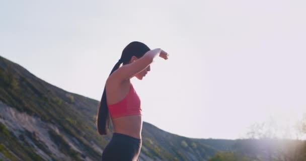 Bella donna con un corpo in forma praticare i suoi esercizi di allenamento in natura si è fermata per un momento per godersi la vista e continuare il suo allenamento — Video Stock