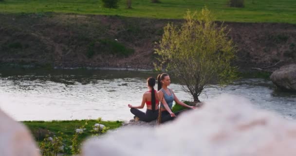 Em lugar incrível na natureza ao lado de um grande lago jovens senhoras atraentes praticando meditação ioga concentrada eles apreciando o tempo — Vídeo de Stock