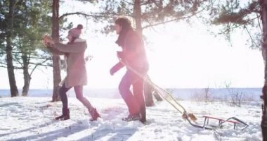 Güneşli bir kış gününde çekici bir çift bir kızak ile telefondan fotoğraf çekerken karlı ormanda bir yürüyüş var onlar mutlu ve çok heyecanlıyız