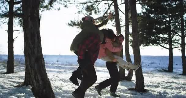 Glad leende stor grupp damer och killar har en bra tid på den snöiga skogen damer är på bak platsen av sina pojkvänner och njuter av tiden tillsammans — Stockvideo