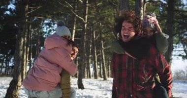 Güzel bir gülümseme ile çok etnik çiftler karlı bir ormanın ortasında birlikte zaman zevk onlar adamın arkasındaki orman bayanlar yürürken heyecanlı