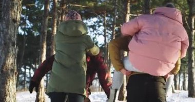 Mutlu çiftler bir kış günü birlikte zaman zevk çocuklar sırtlarında bayanlar alarak ve karlı ormanda bir yürüyüşe gidiyor