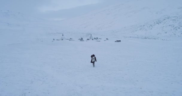 Vista aérea da vida siberiana no meu acampamento de yurts, homem andando pela neve vestindo roupas de pele . — Vídeo de Stock