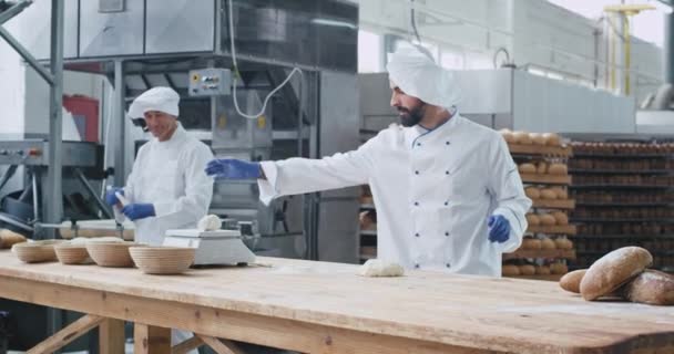 Goed uitziende Bakker en zijn chef-kok genieten van het werk jonge Baker dansen en genieten van de tijd terwijl het bereiden van het deeg voor het bakken — Stockvideo