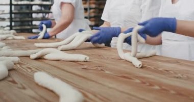 Bir fırın mutfak gıda sektöründe ekmek pişirme için uzun hamur parçaları oluşturan profesyonel fırıncılar