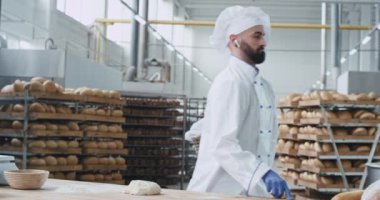 Ekmek dans pişirme ve kablosuz kulaklık, arka plan büyük sanayi makinesi ve pişmiş ekmek müzik dinleme için hamur hazırlarken Fırın fabrika hevesli dans fırıncı şef