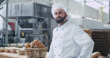 Ticari bir mutfak fırın, organik ekmek ile arka plan vintage sepet kamera önünde güzel gülümseyen sakallı karizmatik fırıncı adam Portresi. yavaş hareketler