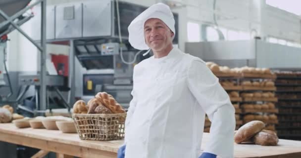 Aantrekkelijke oude Baker man portret glimlachend groot in een bakkerij-industrie hij stak de handen over en geniet van de tijd op zijn werkplek — Stockvideo