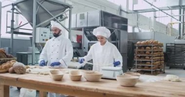Çalışan iki fırıncılar çok ticari bir fırın fabrikasında ekmek pişirme için hamur parçaları oluşturan karizmatik konsantre