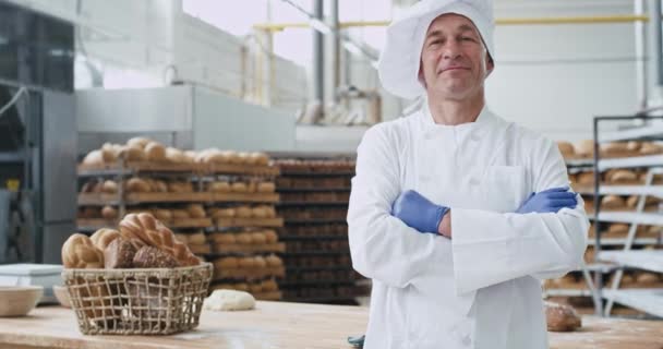 Charismatic velho padeiro homem em um uniforme elegante olhando direto para a câmera e sorrindo para a indústria da padaria mostrando grande como — Vídeo de Stock