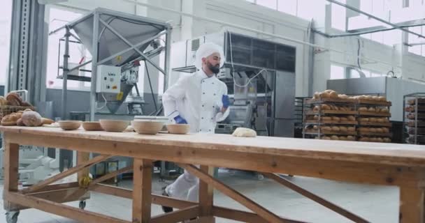 Großaufnahme einer Großbäckerei, die lustige Bäcker mit Bart tanzt, während sie den Teig für das Brotbacken vorbereitet — Stockvideo