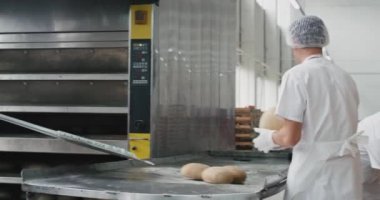 Fırıncı şef ve fırın fabrikasında yaptığı iki yardım endüstriyel fırın makinesinden pişmiş ekmek çıkarmak ve raflara yük