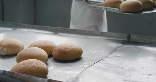 Detalles en una fábrica de panadería descargó el pan en un estante especial, trabajador trabajando uniforme blanco especial — Vídeo de stock