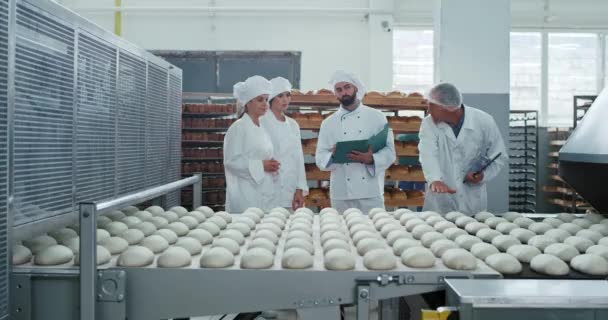 Čas setkání v pekárnu starý technik kontroluje kvalitu těsta a vysvětluje něco o pekařství a Pomocníkovi — Stock video