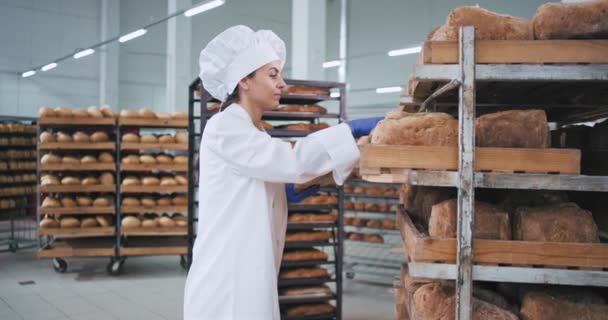 Žena Baker je velmi atraktivní místo na objednávku čerstvě pečeného chleba, který nosí ve stylové uniformě pro pekař — Stock video