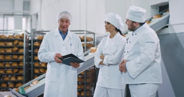 ベーカリー業界の自動コンベアエンジニアがパン屋のシェフに機械の使い方を説明 — ストック動画