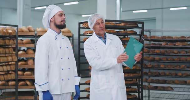 Gespräch zwischen Bäcker und altem Mann Lebensmitteltechniker in einer Bäckerei sie plaudern Ingenieur erklären etwas, um den Bäcker — Stockvideo