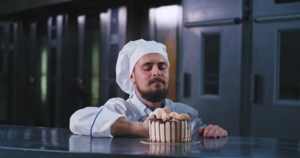 A lenyűgöző jó kinézetű ember a bajusz visel főzőedényben kalap, csákány az ujjával ebben a finom süteményt — Stock videók