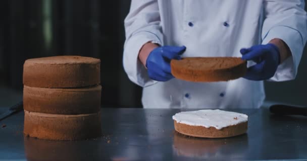 Een close-up van een grote Bakker in koks kledij de onderste helft van de afgeroomde taart met de top niet afgeroomde helft, dan verplaatsen opzij, de taart op zoek zeer goddelijk — Stockvideo