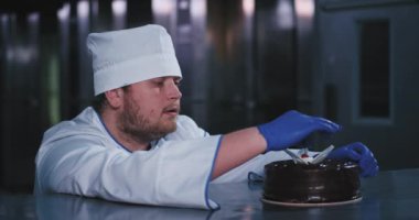 Bir tombul yüzlü büyüleyici fırıncı adam bir pasta kırmızı kiraz aldı ve ona büyüleyici bakıyor