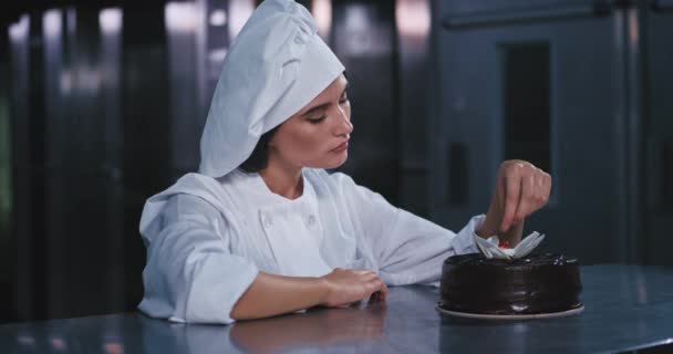 Красивая молодая женщина в костюме пекаря держит красный глаз, ловит вишенку в руке и удивленно смотрит на нее — стоковое видео