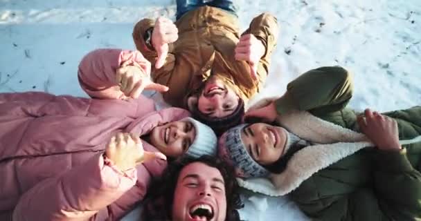 Charismatique et souriant grand groupe d'amis profiter du temps ensemble en utilisant une caméra pour faire quelques selfies ils se couchent sur le sol sur un champ neigeux — Video