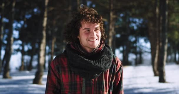 カメラの前で冬のポートレートで一人旅をしながら大きく微笑み、その瞬間を楽しむ巻き毛を持つカリスマ的な男 — ストック動画