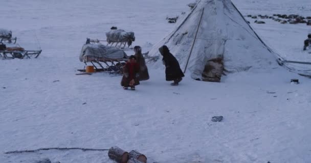 Primer plano jugando divertido tres niños pequeños del campamento de yurtas siberianas, al lado del trineo en un día nevado, que tienen un buen rato juntos — Vídeo de stock