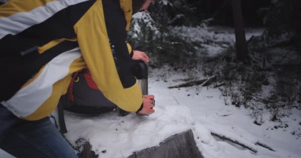 Крупные планы молодого туриста, держащего железную чашку посреди заснеженного леса, который наслаждается видом и чувствует себя расслабленным и счастливым — стоковое видео
