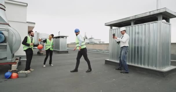 Un jeune homme beau danse pendant que deux autres travailleurs une femme et un homme profitent de toute l'atmosphère amusante et prennent deux verres — Video