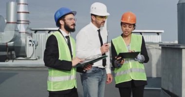 İnşaat endüstrisinden bir grup mühendis ve mimar, genç bir işadamıyla tablet ve çarşaflardan inşa planlarını inceliyor.