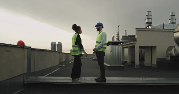 Vackra par arkitekter multietniska på taket av byggarbetsplatsen man göra ett förslag för sin kvinna de bär en säkerhetsutrustning hjälmar hon var mycket imponerad och glad kramar varje — Stockvideo