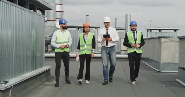 Charismatische multiethnische Menschen zwei Unternehmer Ingenieur und Architekt analysieren und diskutieren den Plan der Baustelle tragen sie einen Schutzhelm — Stockvideo