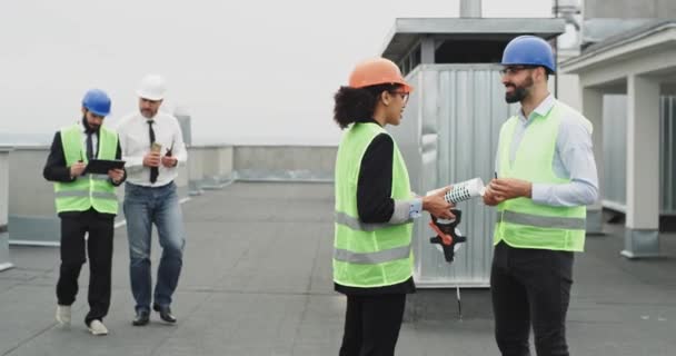 Skupina dělníků na staveništi inženýr podnikatelé mají schůzku na střeše staveniště s bezpečnostní přilbou, kterou drží za ruce a začínají si povídat