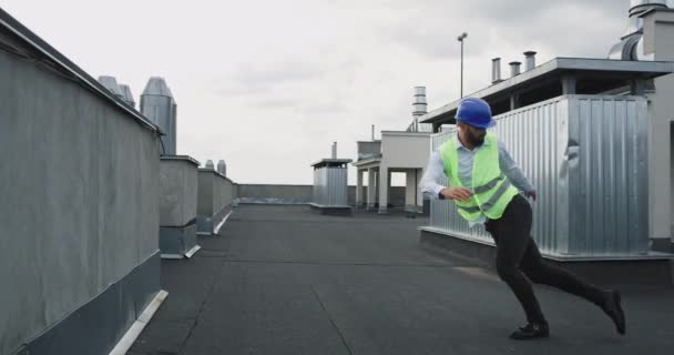 Στην ταράτσα του εργοταξίου νέος καλός αρχιτέκτονας ή μηχανικός χορός ενθουσιασμένος ενώ φορώντας ένα κράνος ασφαλείας — Αρχείο Βίντεο