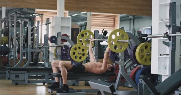 In a sport gym guy doing the workout lifting up the weights hard he working well , healthy lifestyle — Stock Video