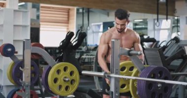 Yakışıklı bir atletik adam bir ağırlık çubuğuüzerinde ağırlık koyarak, o göğsünde ve vücudunda dövmeler var