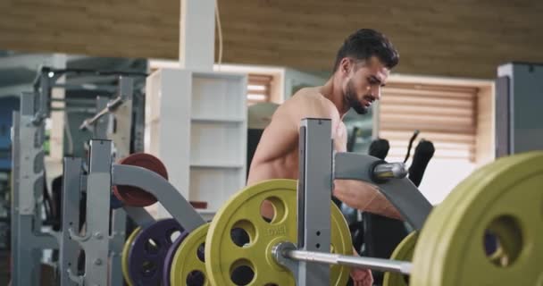 Een betoverende jonge gebouwde man, doet wat zwaar tillen om zijn biceps en ABS op te bouwen — Stockvideo